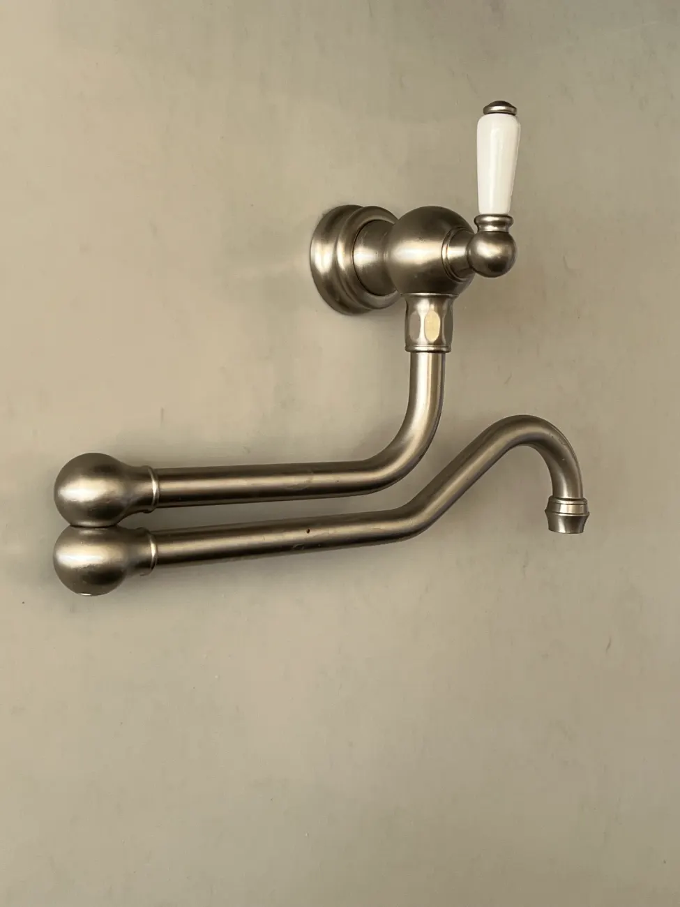 Brushed nickel pot filler tap above a kitchen range